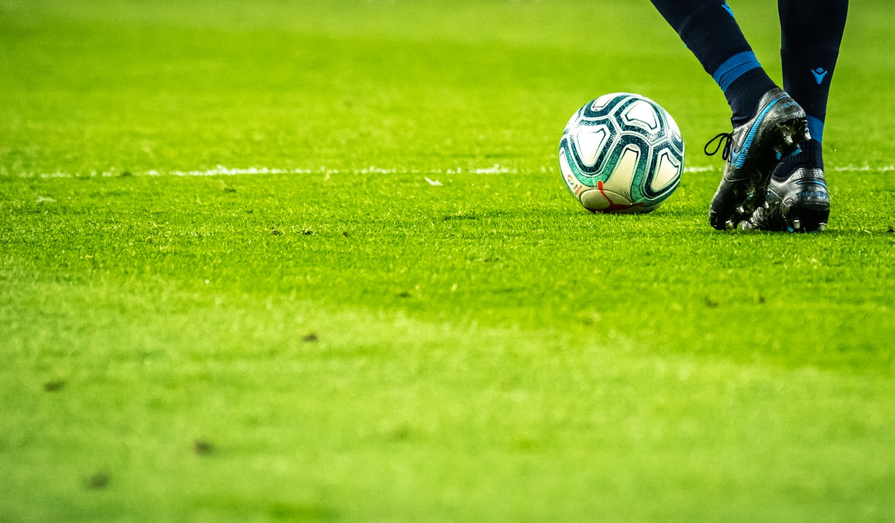 A soccer ball at a young player's feet on the pitch